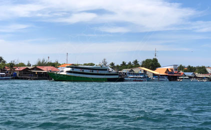 Colorido ferri de pasajeros y barcas de madera amarrados en un muelle tropical de aguas turquesas