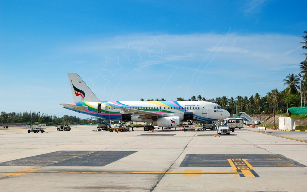 Airbus A319 di Bangkok Air parcheggiato sulla pista di un aeroporto tropicale con palme e personale di terra