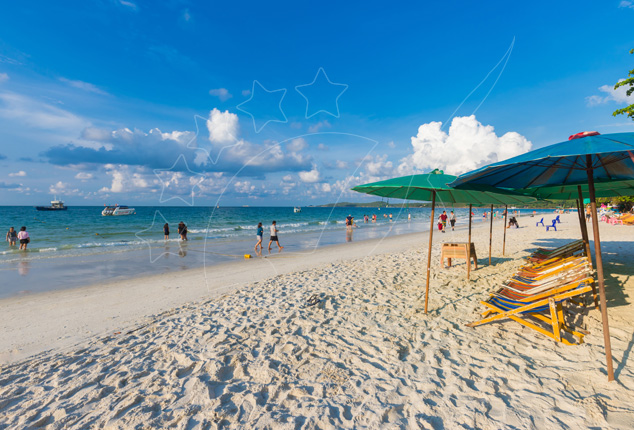 White sand beach with green and blue umbrellas, wooden loungers, distant swimmers and speedboats offshore