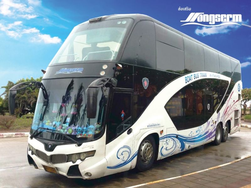 รถโค้ชสองชั้นสีขาวของ Songserm ลายคลื่นสีน้ำเงิน มีข้อความ "Boat Bus Train" จอดบนลานยางมะตอยใต้ฟ้าสีคราม